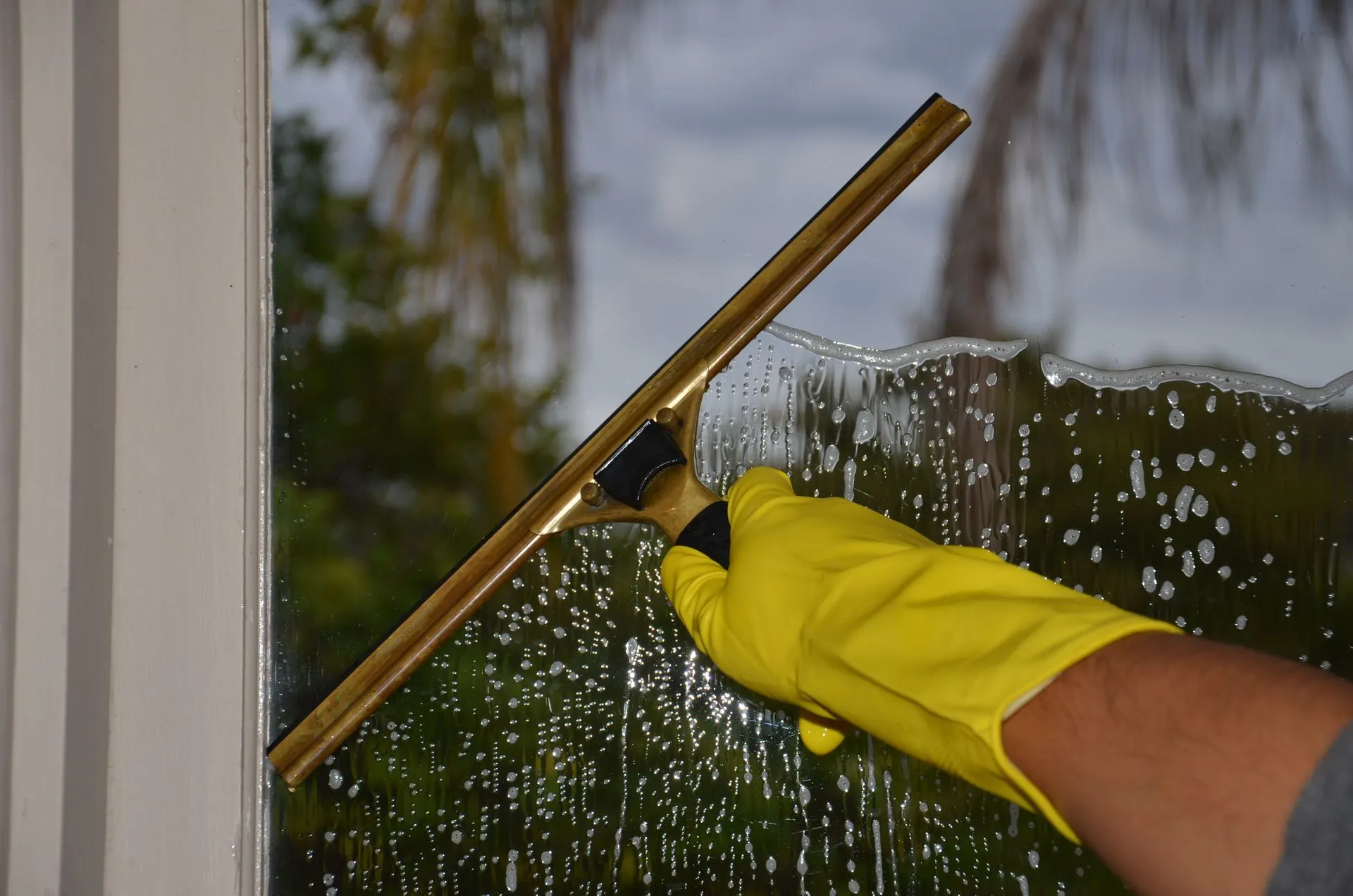 Gloved hand cleaning a window with a squeegee